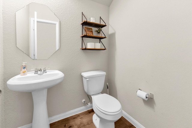 bathroom with toilet, wood-type flooring, and sink