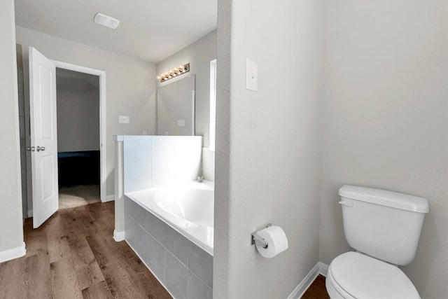 bathroom featuring toilet, a relaxing tiled tub, and hardwood / wood-style flooring