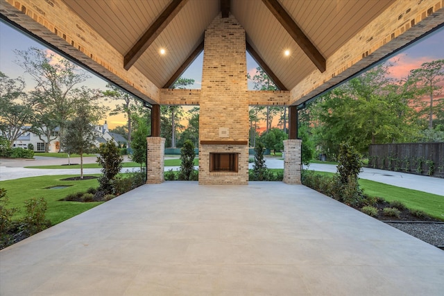 patio terrace at dusk with a gazebo, an outdoor brick fireplace, and a yard