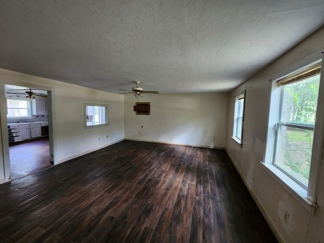 unfurnished living room featuring dark wood-type flooring, a textured ceiling, and ceiling fan