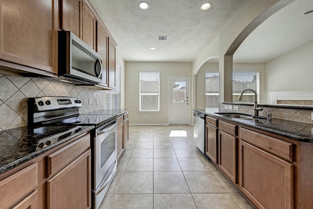 kitchen with dark stone countertops, tasteful backsplash, stainless steel appliances, and sink