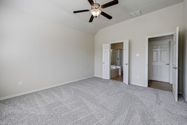 unfurnished bedroom with vaulted ceiling, dark colored carpet, ensuite bathroom, and ceiling fan