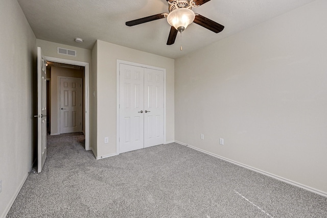 unfurnished bedroom featuring a closet, carpet floors, a textured ceiling, and ceiling fan