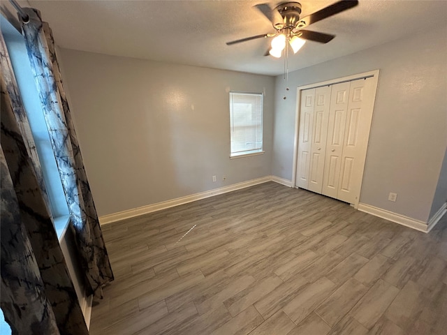 unfurnished bedroom with a textured ceiling, a closet, hardwood / wood-style flooring, and ceiling fan