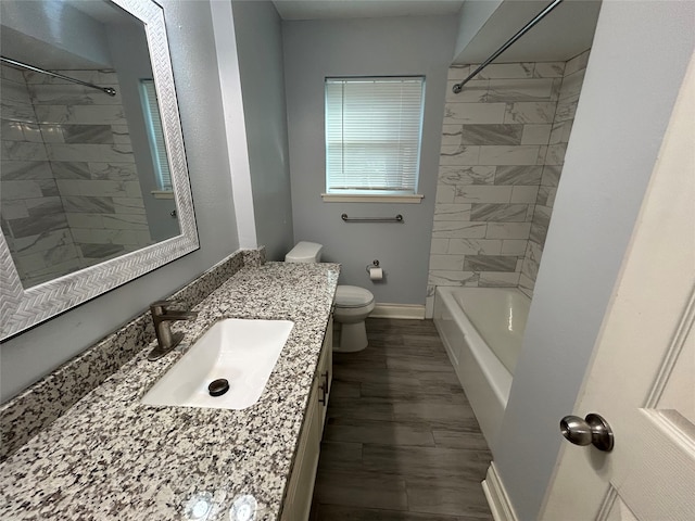 full bathroom featuring vanity, hardwood / wood-style flooring, toilet, and tiled shower / bath combo