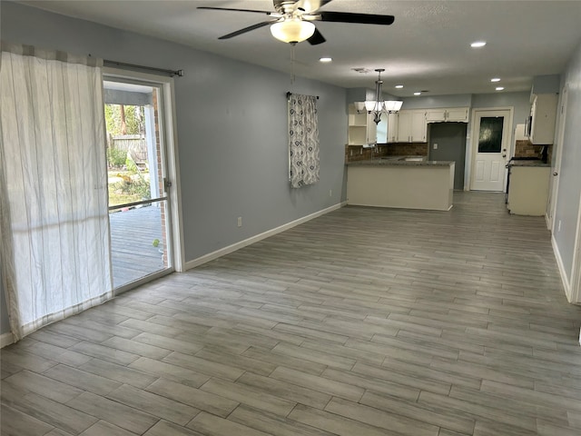 unfurnished living room with light hardwood / wood-style flooring and ceiling fan with notable chandelier