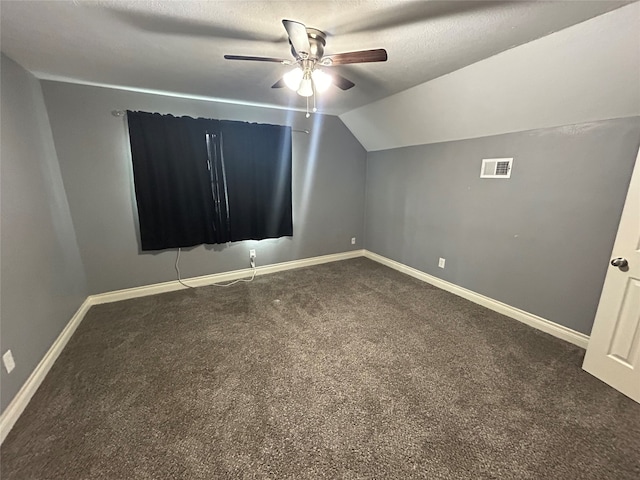 unfurnished room with dark colored carpet, ceiling fan, a textured ceiling, and vaulted ceiling