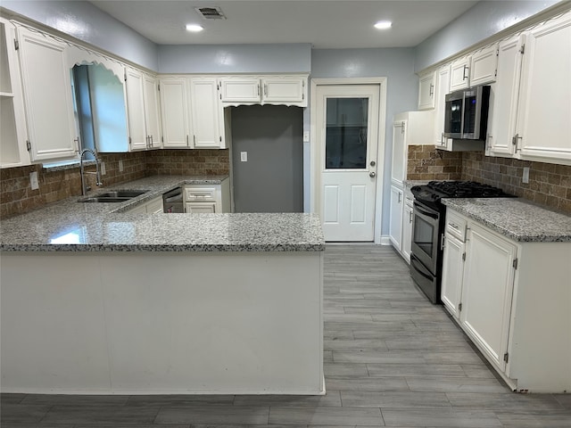 kitchen featuring kitchen peninsula, light stone countertops, sink, and appliances with stainless steel finishes