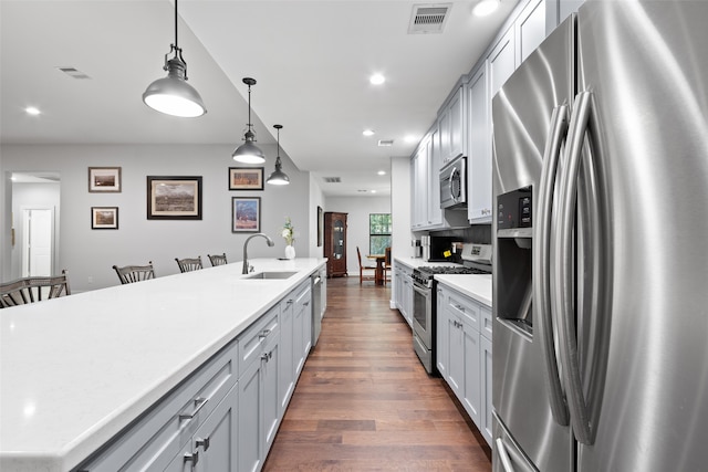 kitchen featuring appliances with stainless steel finishes, sink, pendant lighting, dark hardwood / wood-style floors, and a breakfast bar area