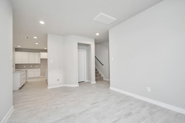 unfurnished living room with stairway, visible vents, recessed lighting, and baseboards
