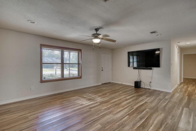 unfurnished living room featuring ceiling fan, light wood-type flooring, and a textured ceiling