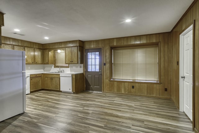 kitchen with dishwasher, wood walls, sink, dark hardwood / wood-style floors, and stainless steel fridge