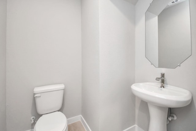 bathroom featuring a sink, visible vents, toilet, and baseboards