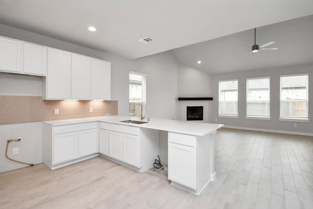 kitchen with backsplash, a sink, visible vents, a peninsula, and open floor plan
