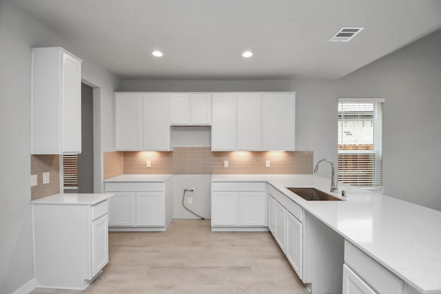 kitchen featuring recessed lighting, decorative backsplash, a sink, visible vents, and a peninsula