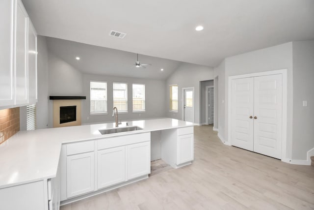 kitchen featuring a sink, visible vents, ceiling fan, open floor plan, and vaulted ceiling