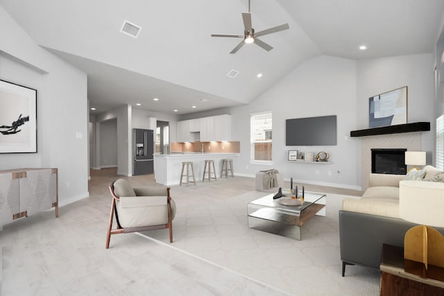 living area featuring visible vents, ceiling fan, high vaulted ceiling, and baseboards