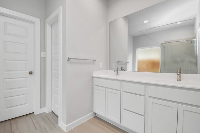 bathroom with double vanity, wood finished floors, a stall shower, and a sink