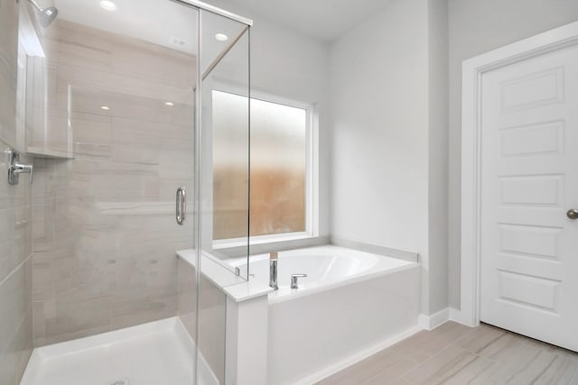 bathroom with a garden tub, a stall shower, and baseboards