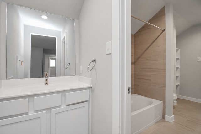 full bathroom featuring vanity, toilet, lofted ceiling, and tiled shower / bath