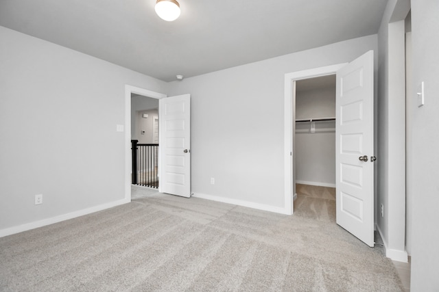 unfurnished bedroom featuring a spacious closet, light carpet, and a closet