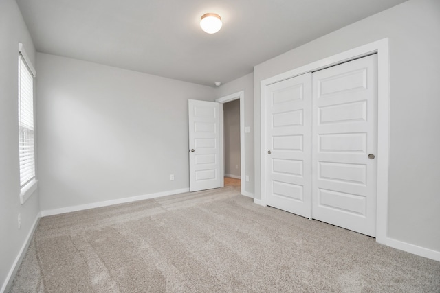 unfurnished bedroom featuring a closet, light carpet, and multiple windows