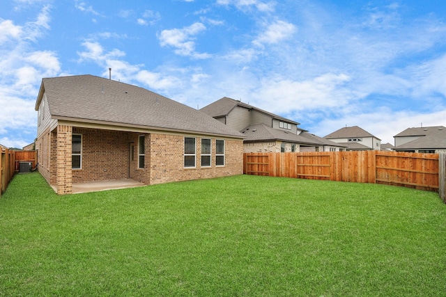 rear view of house with central AC unit, a patio area, a fenced backyard, a lawn, and brick siding