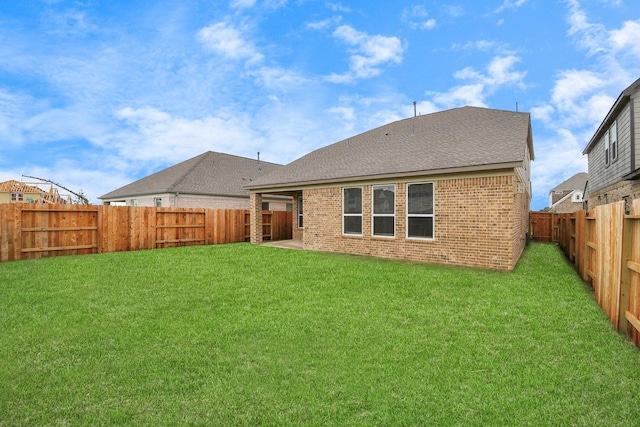 back of property featuring brick siding, a fenced backyard, and a lawn