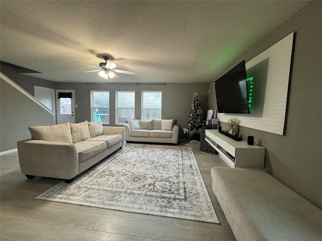 living room featuring ceiling fan and a textured ceiling