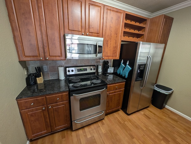 kitchen with appliances with stainless steel finishes, light hardwood / wood-style flooring, decorative backsplash, and dark stone countertops