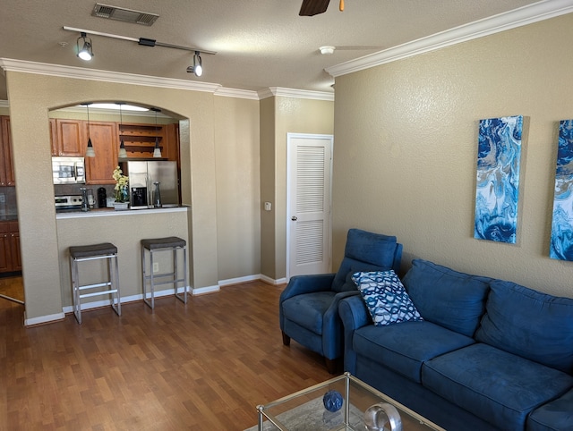 living room with a textured ceiling, ceiling fan, hardwood / wood-style flooring, ornamental molding, and track lighting