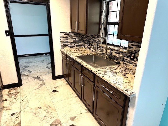 kitchen with decorative backsplash, sink, and light stone counters