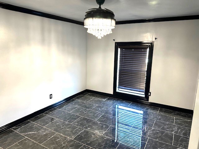 unfurnished room with crown molding and a notable chandelier