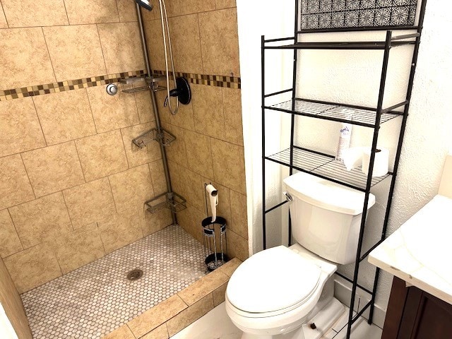 bathroom with vanity, tiled shower, and toilet