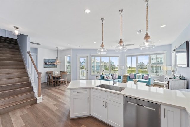 kitchen with dishwasher, white cabinetry, light hardwood / wood-style flooring, and pendant lighting