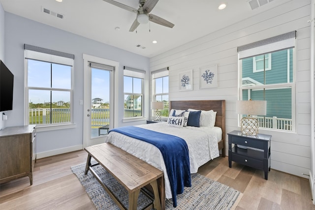 bedroom with wooden walls, access to exterior, light wood-type flooring, and ceiling fan