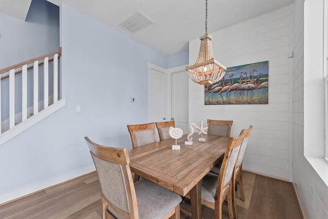 dining space with hardwood / wood-style floors and a chandelier