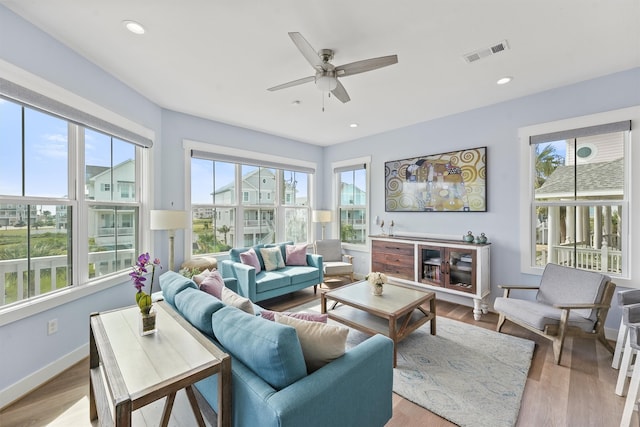 living room with light wood-type flooring, a healthy amount of sunlight, and ceiling fan