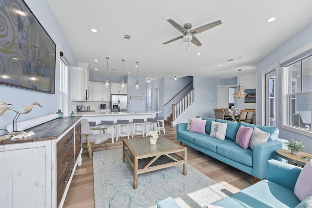 living room featuring light hardwood / wood-style floors, sink, and ceiling fan