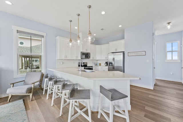 kitchen featuring appliances with stainless steel finishes, a wealth of natural light, and white cabinets