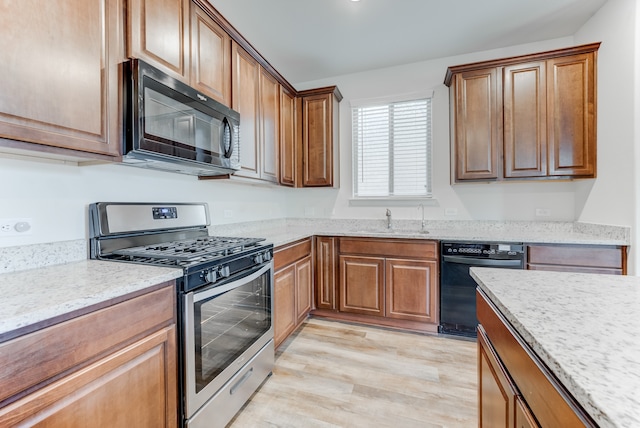 kitchen featuring light hardwood / wood-style floors, light stone countertops, black appliances, and sink