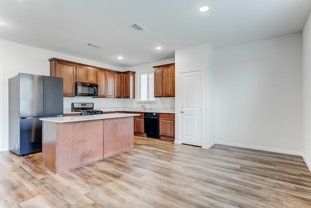 kitchen featuring light hardwood / wood-style flooring, a center island, black appliances, and sink