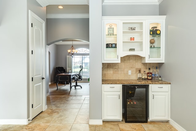 bar featuring white cabinetry, wine cooler, dark stone countertops, and crown molding