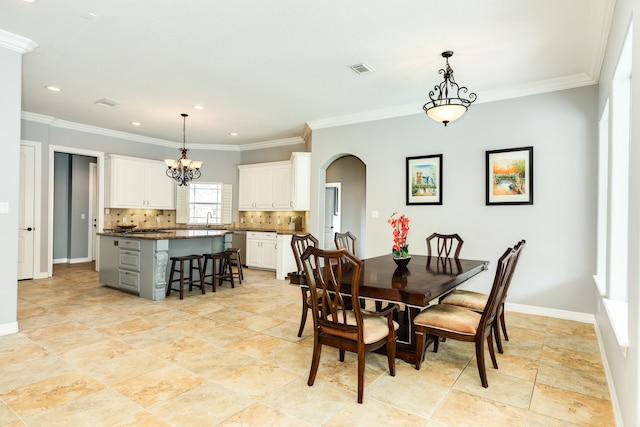 dining area featuring ornamental molding, sink, and a chandelier