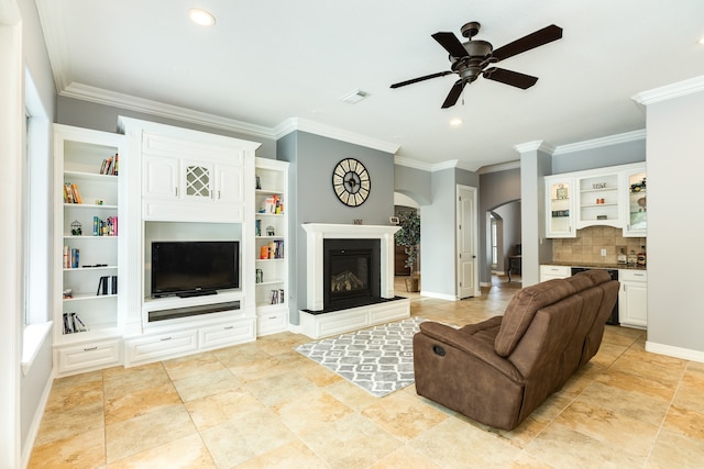 living room with crown molding, built in features, and ceiling fan