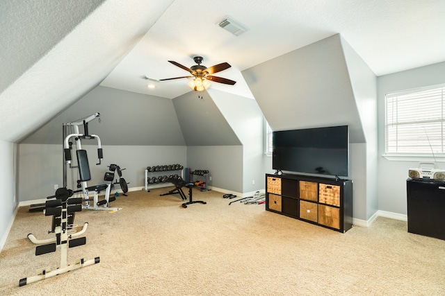 exercise room featuring ceiling fan, light carpet, a textured ceiling, and vaulted ceiling