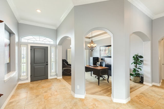 entryway featuring light hardwood / wood-style flooring, a towering ceiling, ornamental molding, and an inviting chandelier