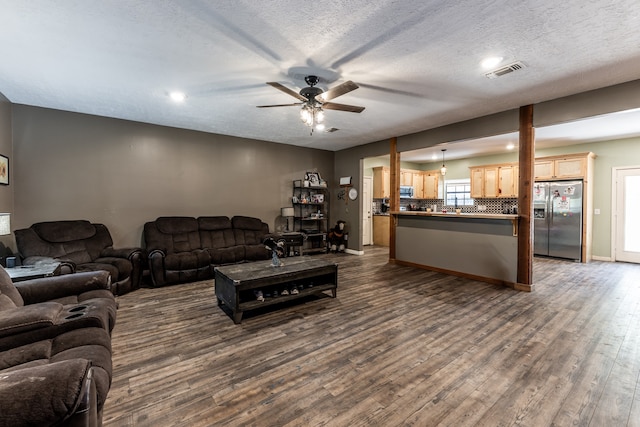 living room featuring a textured ceiling, ceiling fan, plenty of natural light, and dark hardwood / wood-style flooring