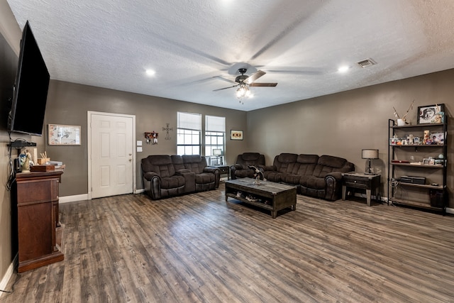 living room featuring ceiling fan, a textured ceiling, and dark hardwood / wood-style floors