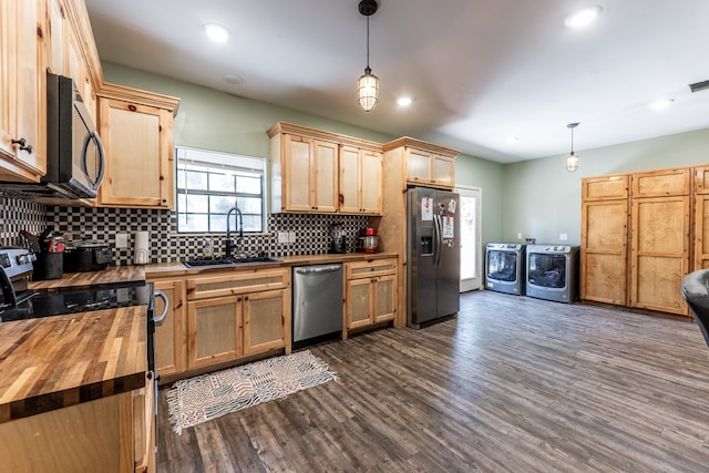 kitchen featuring sink, independent washer and dryer, hanging light fixtures, stainless steel appliances, and wooden counters